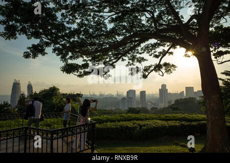 Touristen, die Bilder von Sonnenuntergang über Wolkenkratzer auf dem Mount Faber Park, Singapur Stockfoto