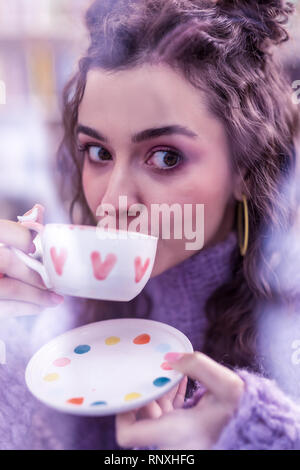 Attraktive dunkelhaarige Frau mit grossen braunen Augen Tasse Tee Stockfoto