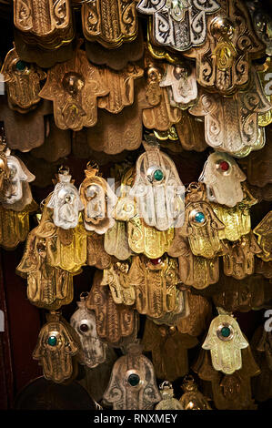 Mehrere vergoldeten Symbole genannt Hamsa oder "Hand Gottes" hängen nach unten zum Verkauf in ein Medina markt Souq in Fes, Marokko. Stockfoto
