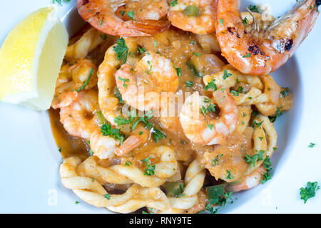 Eine pasta Schüssel mit sardischen Spezialitäten Lorighittas Nudeln mit Meeresfrüchten und Tomatensauce mit frischer Zitrone Keil garniert serviert. Stockfoto