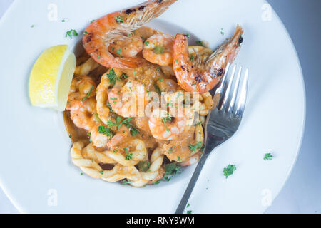 Eine pasta Schüssel mit sardischen Spezialitäten Lorighittas Nudeln mit Meeresfrüchten und Tomatensauce mit frischer Zitrone Keil garniert serviert. Stockfoto