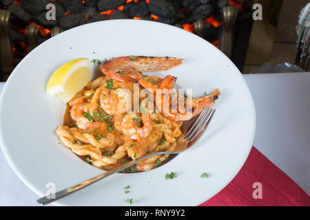 Eine pasta Schüssel mit sardischen Spezialitäten Lorighittas Nudeln mit Meeresfrüchten und Tomatensauce mit frischer Zitrone Keil garniert serviert. Stockfoto