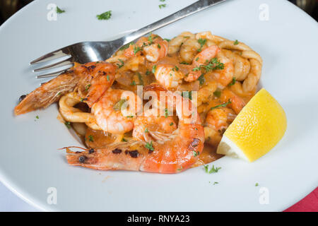 Eine pasta Schüssel mit sardischen Spezialitäten Lorighittas Nudeln mit Meeresfrüchten und Tomatensauce mit frischer Zitrone Keil garniert serviert. Stockfoto