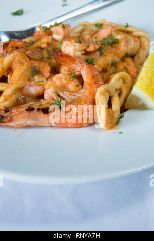 Eine pasta Schüssel mit sardischen Spezialitäten Lorighittas Nudeln mit Meeresfrüchten und Tomatensauce mit frischer Zitrone Keil garniert serviert. Stockfoto