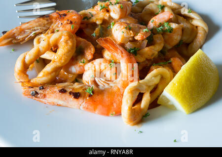 Eine pasta Schüssel mit sardischen Spezialitäten Lorighittas Nudeln mit Meeresfrüchten und Tomatensauce mit frischer Zitrone Keil garniert serviert. Stockfoto