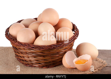 Eier auf einem hölzernen Tisch in einem Weidenkorb auf einem weißen Hintergrund. Stockfoto