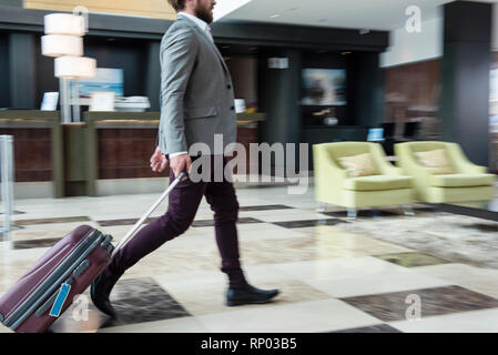 Geschäftsmann mit Koffer mit Rädern Stockfoto