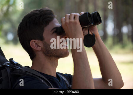 Junger Mann durch ein Fernglas im Wald suchen Stockfoto