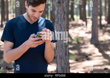 Junger Mann mit Telefon im Wald Stockfoto