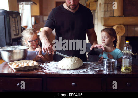 Vater und seine zwei kleinen Helfer. Kinder kochen hausgemachtes Brot mit es Vater Stockfoto