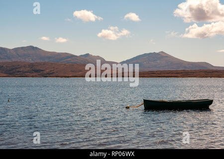Kleines Fischerboot auf dem Loch Biene/Loch Bi mit den Hügeln von South Uist im Hintergrund, Äußere Hebriden, Schottland, Großbritannien Stockfoto
