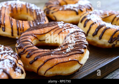 Hausgemachte klassische Donuts mit Schokolade und Kokos Flocken auf einem dunklen Hintergrund. Close Up. Stockfoto