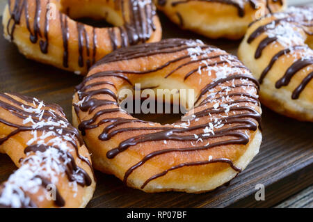 Hausgemachte klassische Donuts mit Schokolade und Kokos Flocken auf einem dunklen Hintergrund. Close Up. Stockfoto