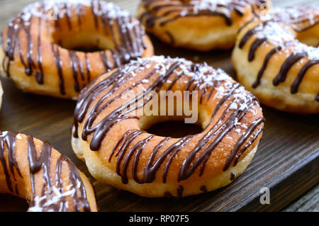 Hausgemachte klassische Donuts mit Schokolade und Kokos Flocken auf einem dunklen Hintergrund. Close Up. Stockfoto