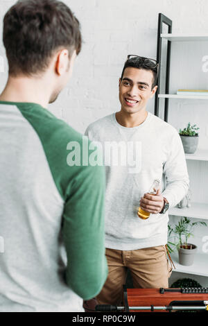 Schönen gemischten Rennen Mann hält eine Flasche Bier und Gespräch mit Freund Stockfoto