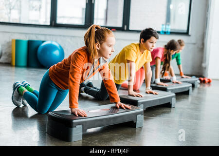 Kinder mit Step Plattformen während Push-up, Übung Stockfoto