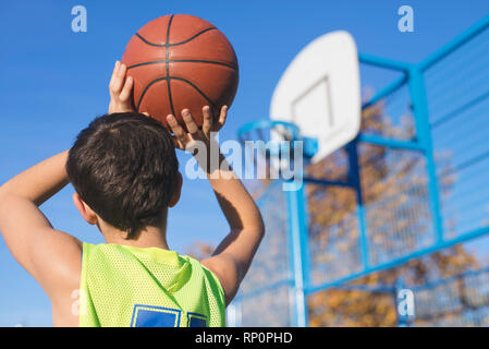 Jugendliche werfen einen Basketball in den Bügel von hinten Stockfoto