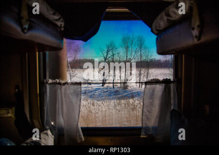 Eine gefrorene Tundra präsentiert sich aus dem Blick aus dem Fenster einer Schlafkabine auf dem Transsibirischen Zug, Russland Stockfoto