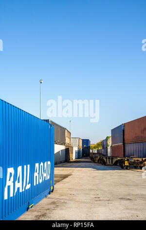 Cargo Container warten auf eine Eisenbahn Plattform entlang einem Güterzug in einem Hafen in den Vororten von Paris, Frankreich. Stockfoto