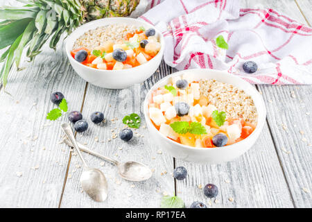 Gesundes Frühstück Haferflocken mit tropischen Früchten und Beeren, auf weißem Holz- Background Copy space Stockfoto
