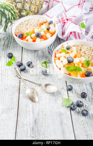 Gesundes Frühstück Haferflocken mit tropischen Früchten und Beeren, auf weißem Holz- Background Copy space Stockfoto