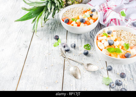 Gesundes Frühstück Haferflocken mit tropischen Früchten und Beeren, auf weißem Holz- Background Copy space Stockfoto