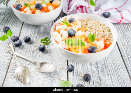Gesundes Frühstück Haferflocken mit tropischen Früchten und Beeren, auf weißem Holz- Background Copy space Stockfoto