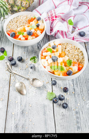 Gesundes Frühstück Haferflocken mit tropischen Früchten und Beeren, auf weißem Holz- Background Copy space Stockfoto