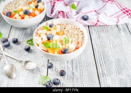 Gesundes Frühstück Haferflocken mit tropischen Früchten und Beeren, auf weißem Holz- Background Copy space Stockfoto