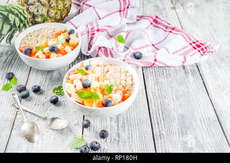 Gesundes Frühstück Haferflocken mit tropischen Früchten und Beeren, auf weißem Holz- Background Copy space Stockfoto