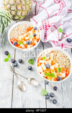 Gesundes Frühstück Haferflocken mit tropischen Früchten und Beeren, auf weißem Holz- Background Copy space Stockfoto