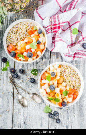 Gesundes Frühstück Haferflocken mit tropischen Früchten und Beeren, auf weißem Holz- Background Copy space Stockfoto