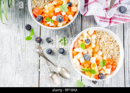 Gesundes Frühstück Haferflocken mit tropischen Früchten und Beeren, auf weißem Holz- Background Copy space Stockfoto