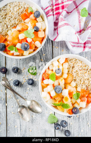 Gesundes Frühstück Haferflocken mit tropischen Früchten und Beeren, auf weißem Holz- Background Copy space Stockfoto