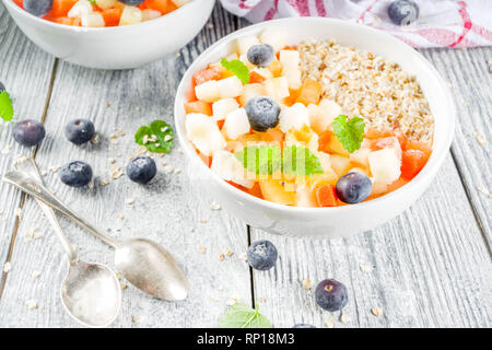 Gesundes Frühstück Haferflocken mit tropischen Früchten und Beeren, auf weißem Holz- Background Copy space Stockfoto