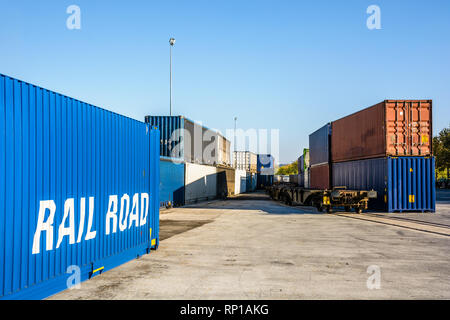 Cargo Container warten auf eine Eisenbahn Plattform entlang einem Güterzug in einem Hafen in den Vororten von Paris, Frankreich. Stockfoto