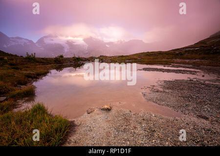 Nebel bei Sonnenaufgang über den Piz Cambrena und alpinen See, Val Dal Bugliet, Berninapass, Kanton Graubünden, Engadin, Schweiz Stockfoto