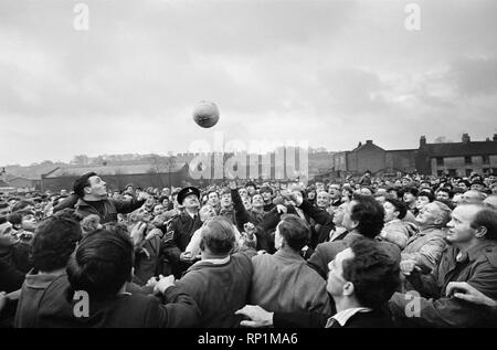 Die traditionelle Royal Faschings Fußballspiel, eine 'mittelalterlich Fußball" Spiel gespielt jährlich am Faschingsdienstag und Aschermittwoch in der Nähe von Ashbourne in Derbyshire. Ehrengast Sir Stanley Matthews' dreht, den Ball, das Spiel für die Dorfbewohner zu starten. 22. Februar 1966. Stockfoto