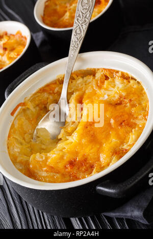 Gebackene Kartoffel auflauf oder Kartoffeln Romanoff mit gebackenen Kartoffeln mit Käse und saurer Sahne schließen Sie die geladenen beginnt in einer Pfanne auf dem Tisch. Vertikale Stockfoto