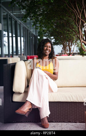 Eine attraktive, stilvolle Afrikanischen brasilianische Frau sitzt auf einem Sessel Stockfoto