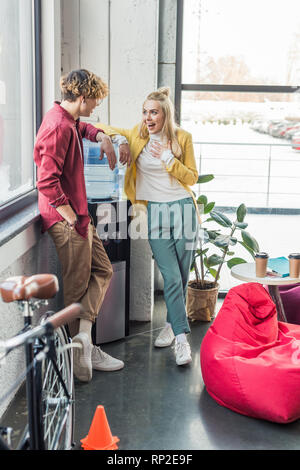 Casual Geschäftsmann und aufgeregt Frau sprechen in loft Büro Stockfoto