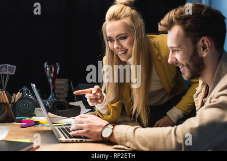 Lächelnd weibliche und männliche IT-Spezialisten mit Laptop im Büro Stockfoto