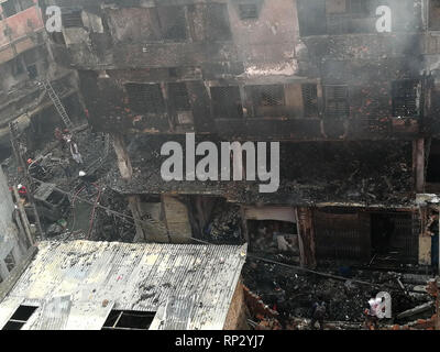 Dhaka, Bangladesch. 21 Feb, 2019. Nach einem Brand, Menschen stehen in der Nähe eines Gebäudes durch die Flammen zerstört. Dutzende Menschen haben ihr Leben verloren in einem Großbrand in Bangladeschs Hauptstadt Dhaka. Dies war sagte am Donnerstag morgen 21.02.2019 durch Kamrul Hasan, der Offizier im Dienst der Feuerwehr und Zivilschutz, der Deutschen Presseagentur. Credit: Mohammad Al-Masum Molla/dpa/Alamy leben Nachrichten Stockfoto