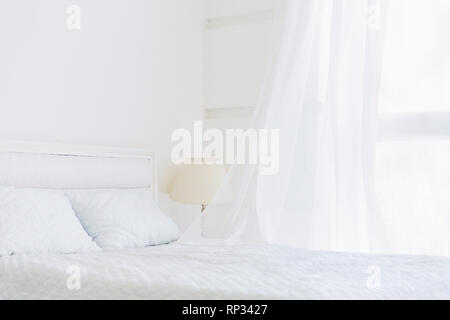 Abstrakte weißen Zimmer mit weißer Bettwäsche, winken Vorhang am Fenster Stockfoto