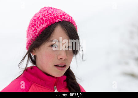Junge asiatische Mädchen mit rosa Hut und Jacke im Schnee Stockfoto