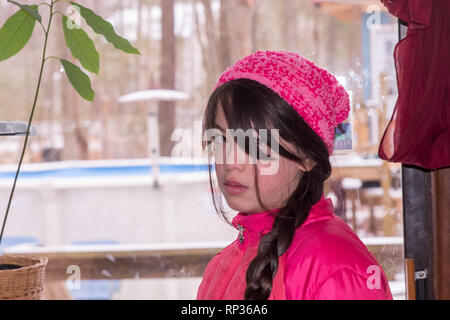 Junge asiatische Mädchen mit rosa Hut und Jacke im Schnee Stockfoto