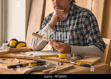 Tischler Planung DIY-Projekt in seiner kleinen Werkstatt für Holzarbeiten Stockfoto