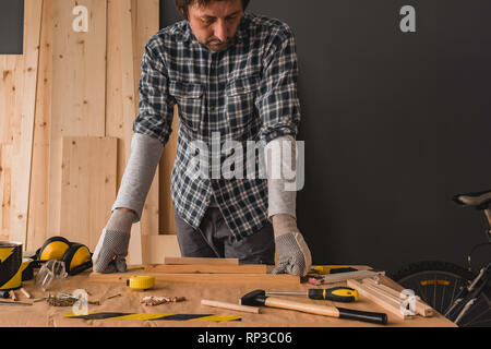 Carpenter plant Holzarbeitprojekt in Werkstatt, über dem Schreibtisch mit Brettern und Tools Stockfoto