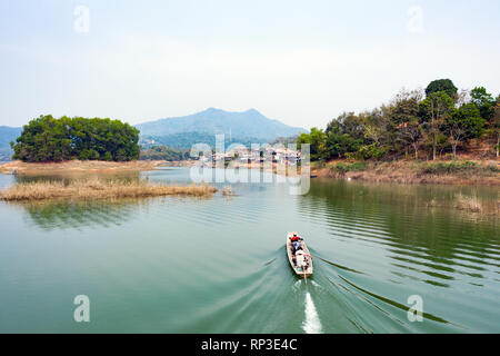 (Sicht von oben) atemberaubenden Luftaufnahme eines traditionellen Long tail Boot mit Touristen an Bord Segeln in den Gewässern des Nam Ngum Stausee. Stockfoto