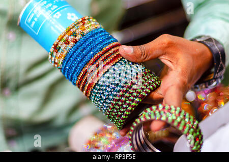 Ein Verkäufer, die eine Sammlung von Hyderabad berühmten bunten/bunte Glas Armbänder/Armreifen zum Verkauf an laad Basar, Hyderabad, Telangana, Indien. Stockfoto